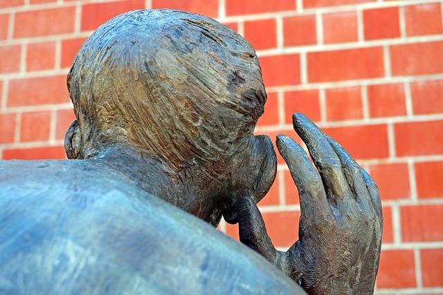 picture of a sculpture, focused on back of head with hand to ear.